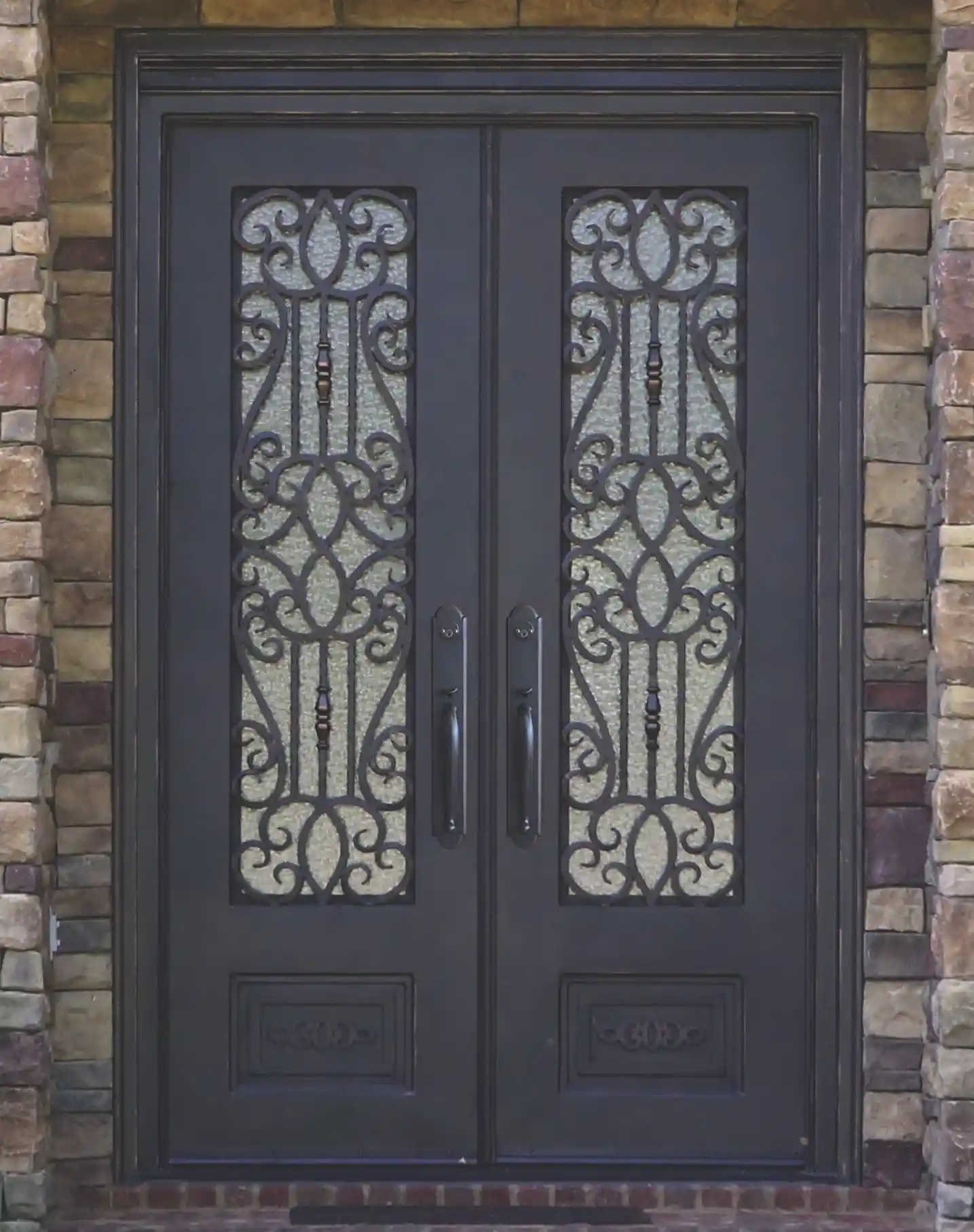 a black iron double door with large panes of glass on each door with intricate black iron swirls on each