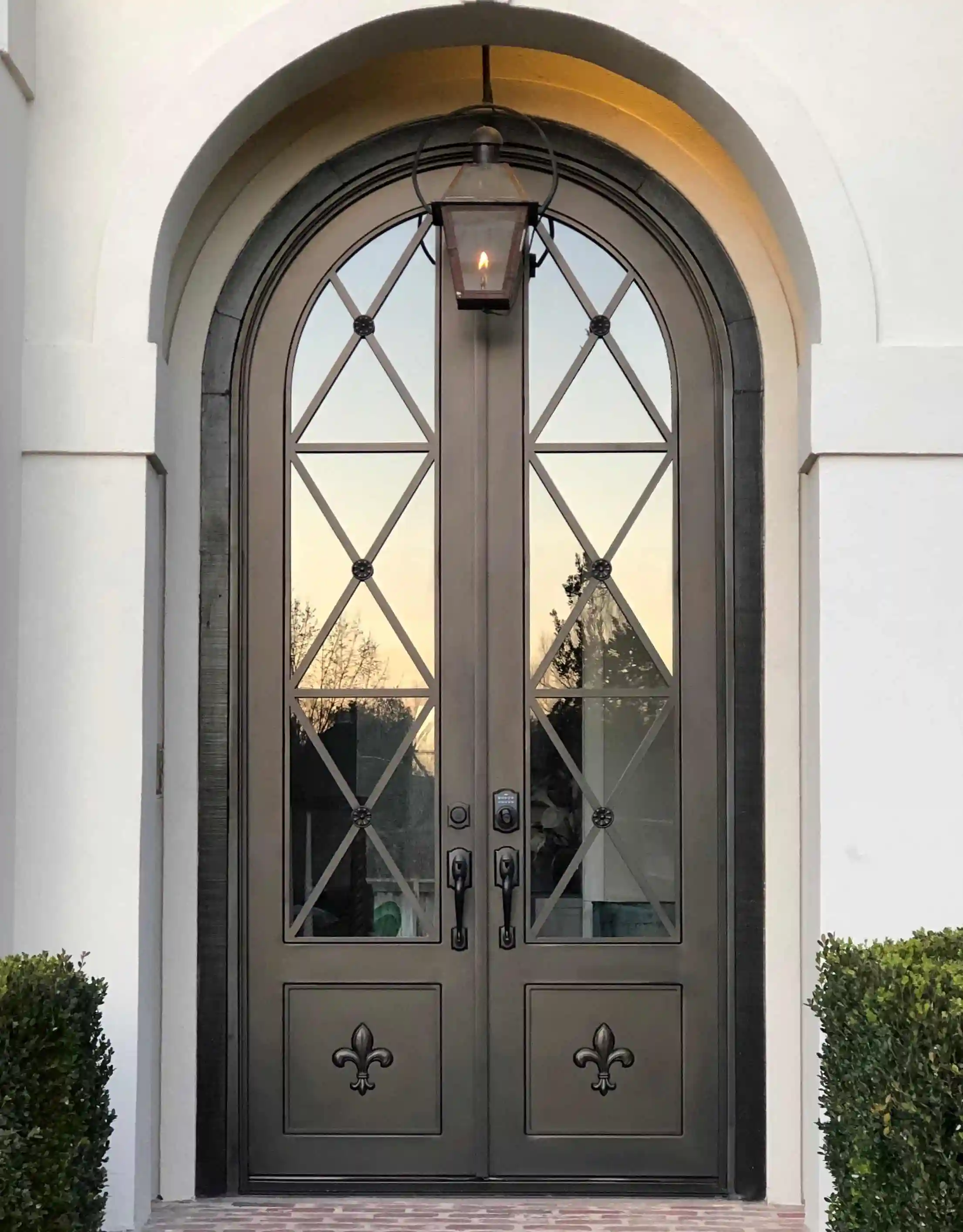 a black iron double door with large panes of glass on each door with black X crossing panels overlayed