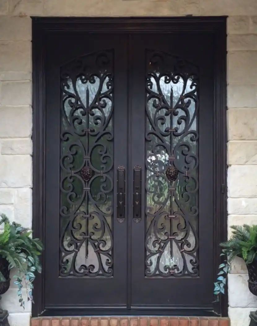 a black iron double entry door with large panes of glass on each door with intricate black iron swirls on each.