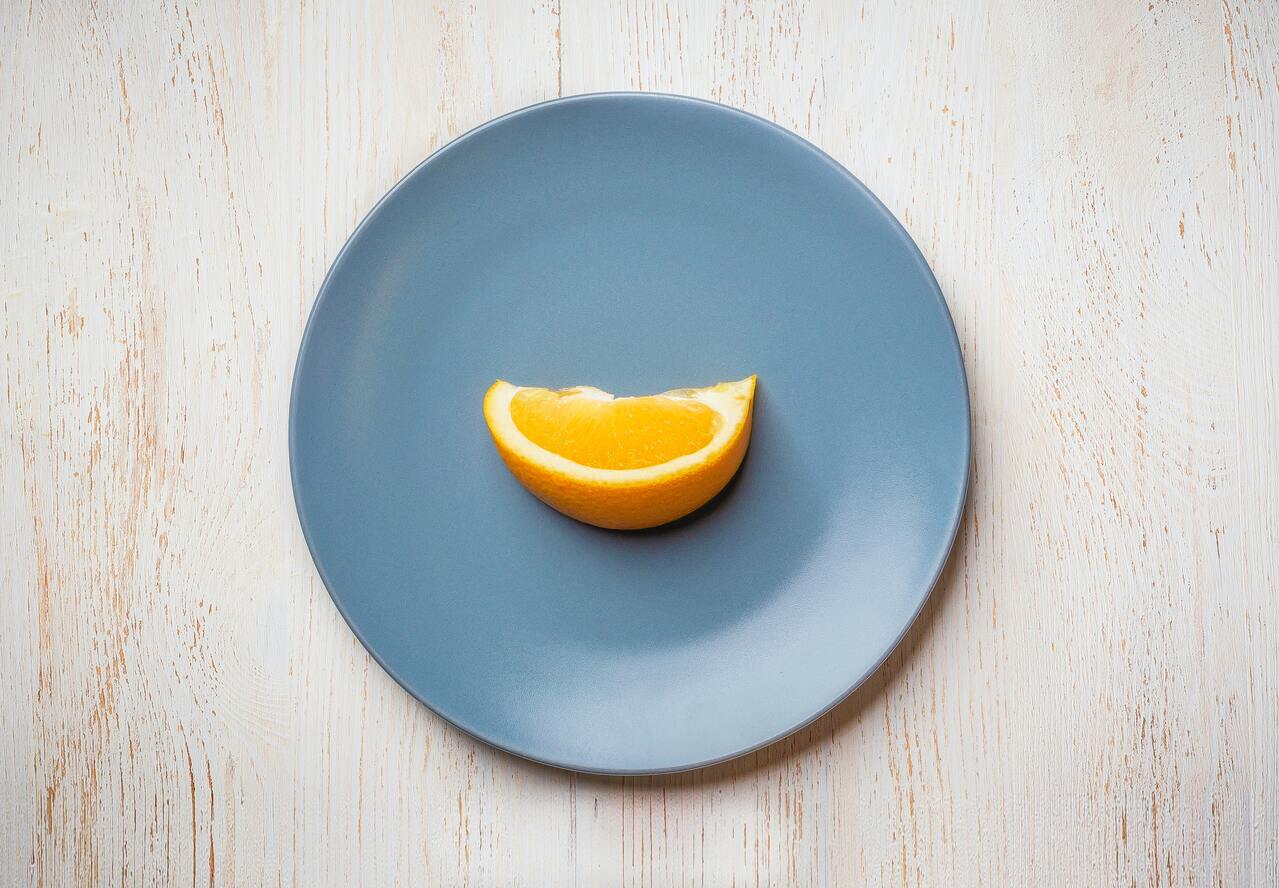 Blauer Teller mit einem Stück Orange