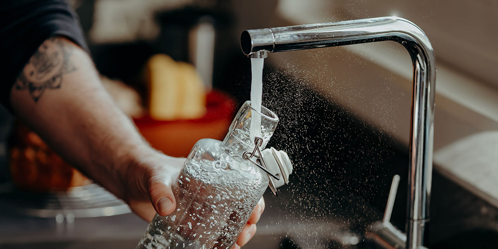 soulbottles wiederverwendbare Glastrinkflasche wird am Wasserhahn mit Leitungswasser befüllt