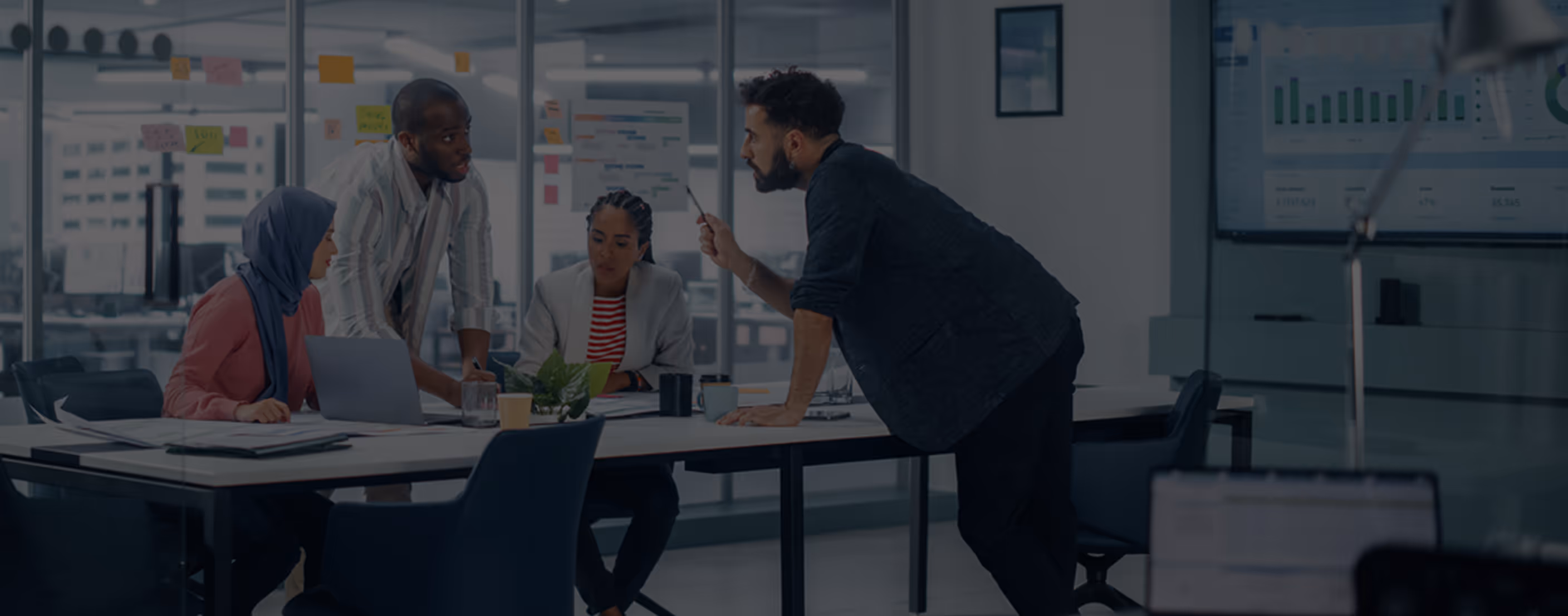 Four diverse colleagues engaged in discussion during a meeting in a modern office.