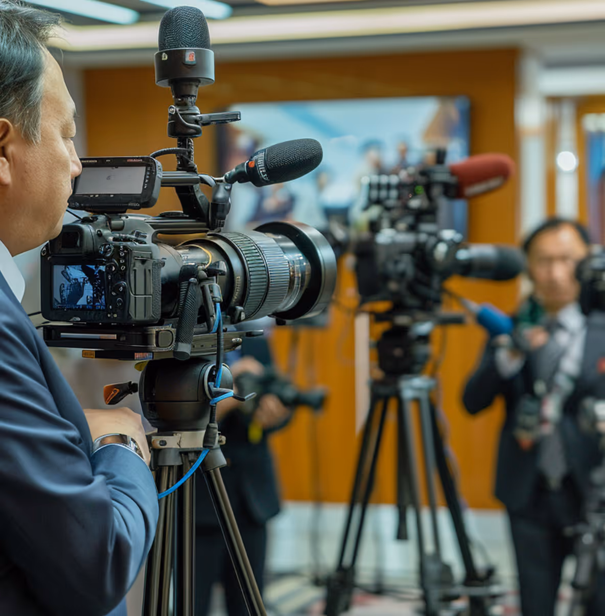 Cameraman operating professional video camera during a press conference or media event.