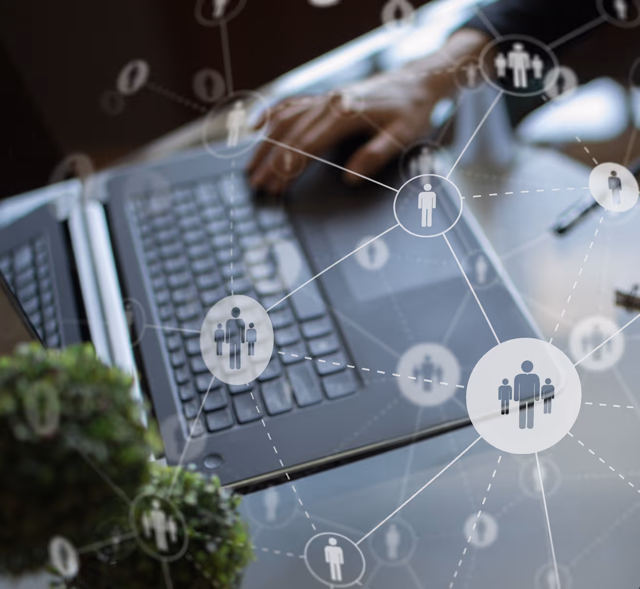 Hand typing on laptop keyboard with digital network icons representing connected people overlay.