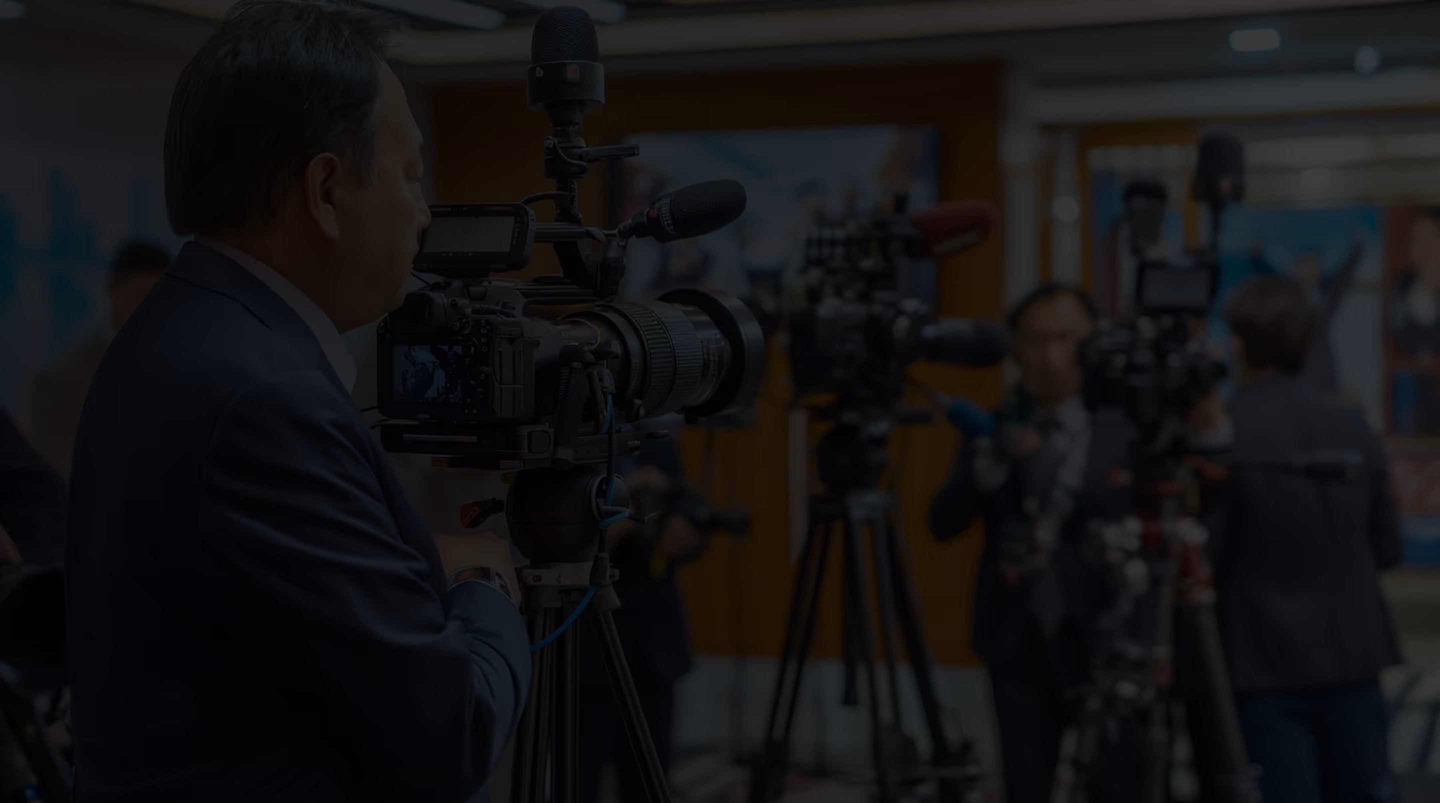 Camera operators filming at an indoor event with multiple professional video cameras on tripods.