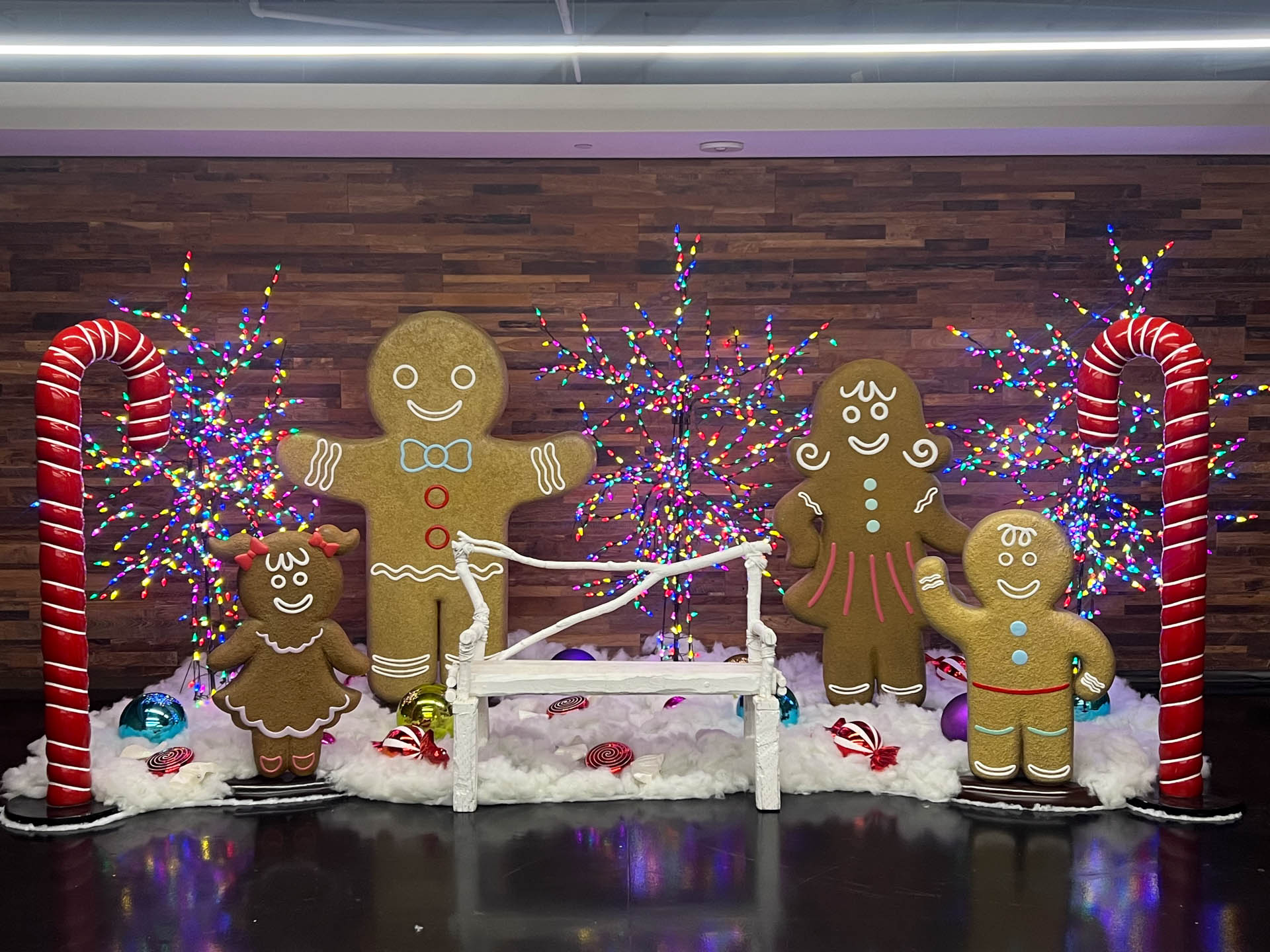 Decorative gingerbread family with candy canes and colorful lights on a wooden backdrop