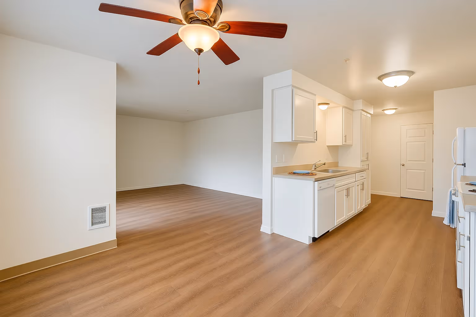 Unfurnished dining and living area with view of kitchen with white cabinets