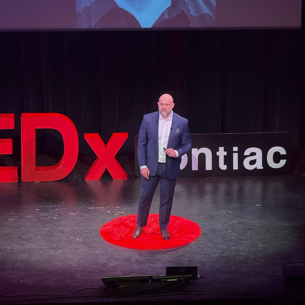 John Patterson delivering "Ask Anything: AI, Emotion, and Influence" at TEDxPontiac, May 2026.