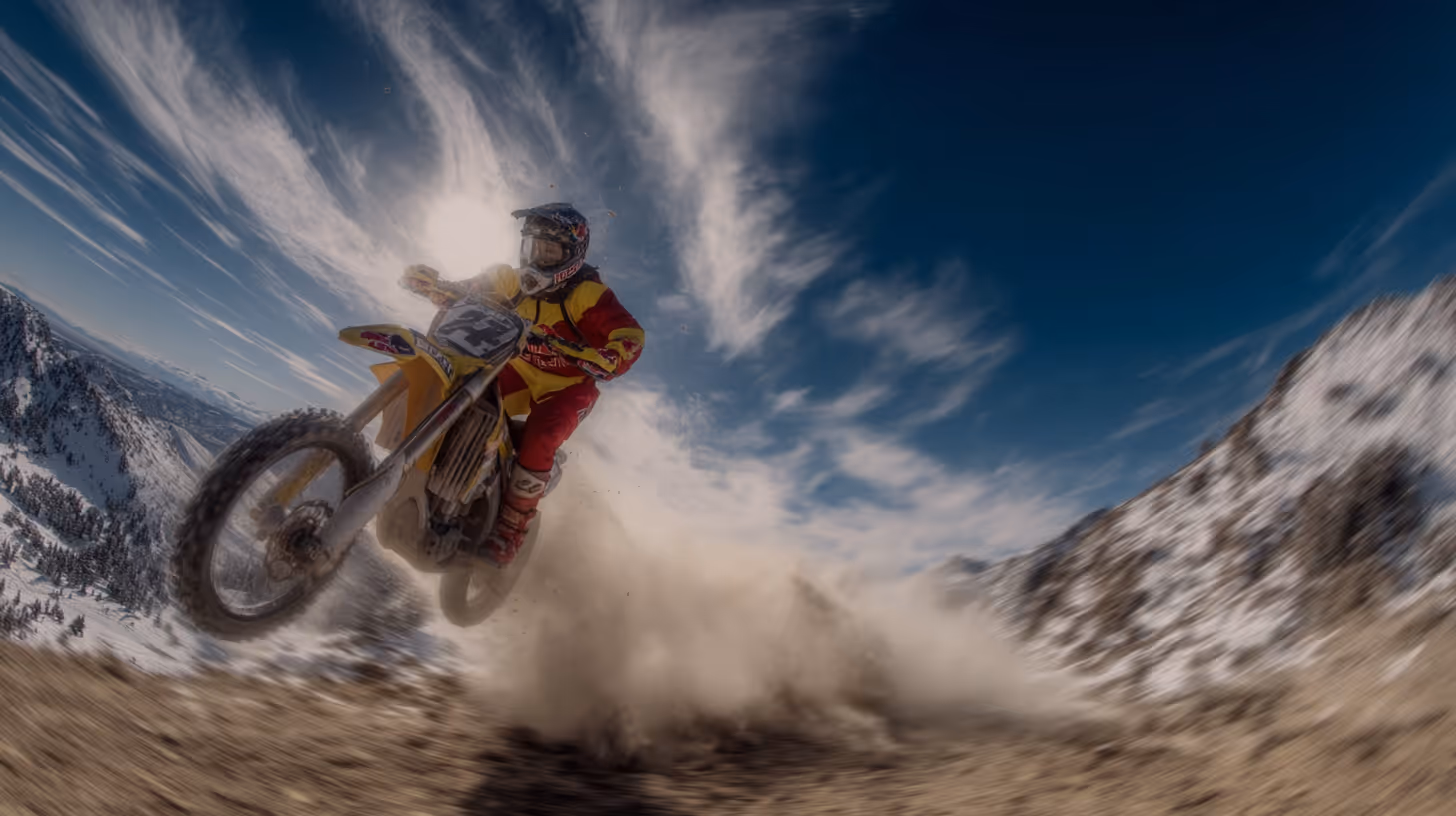 Motorcyclist in red and yellow gear riding a dirt bike kicking up dust with snowy mountains and a blue sky in the background Adrenaline Plus, ai mockup