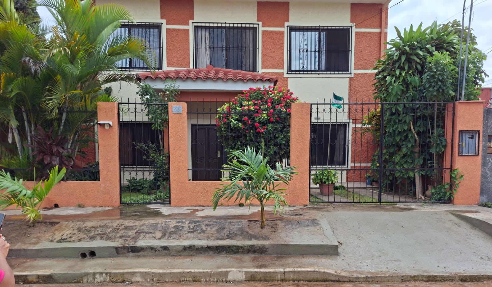 The entrance to a two-storey house with a garden and gate.