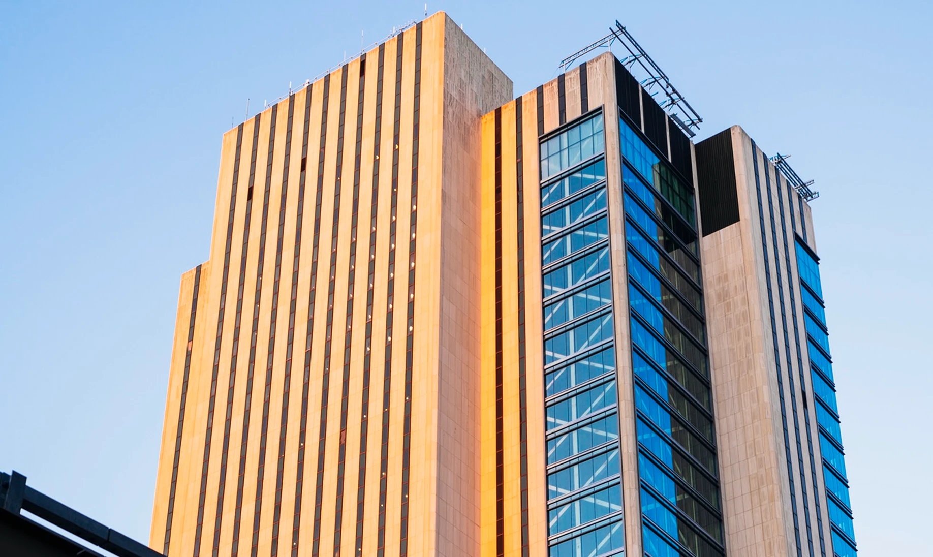 Tall modern office building with vertical stripes and large glass windows reflecting the sky.