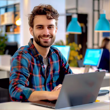 Smiling professional working on laptop in modern IT office environment with computer monitors in background