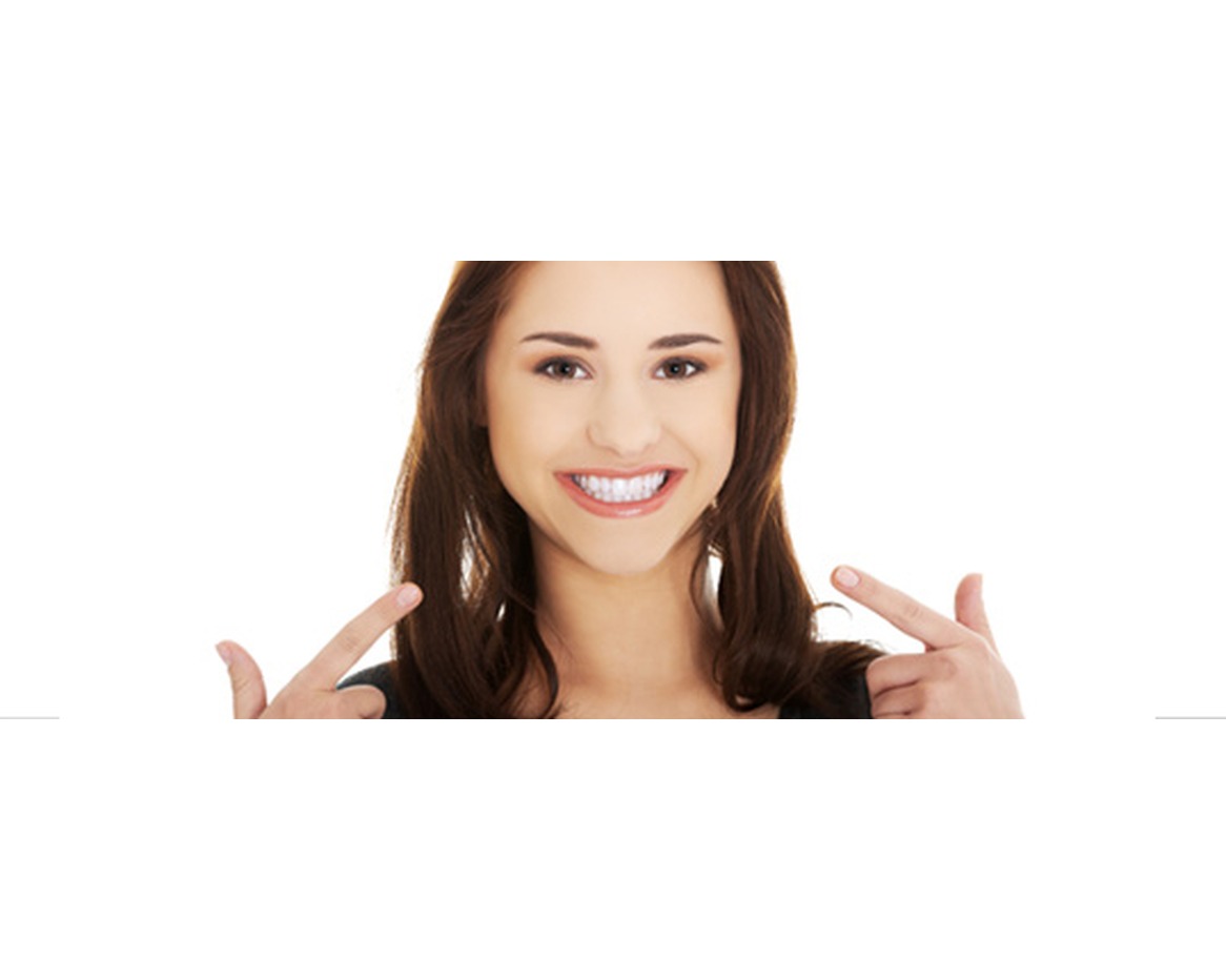 Smiling woman pointing at her bright, even front teeth