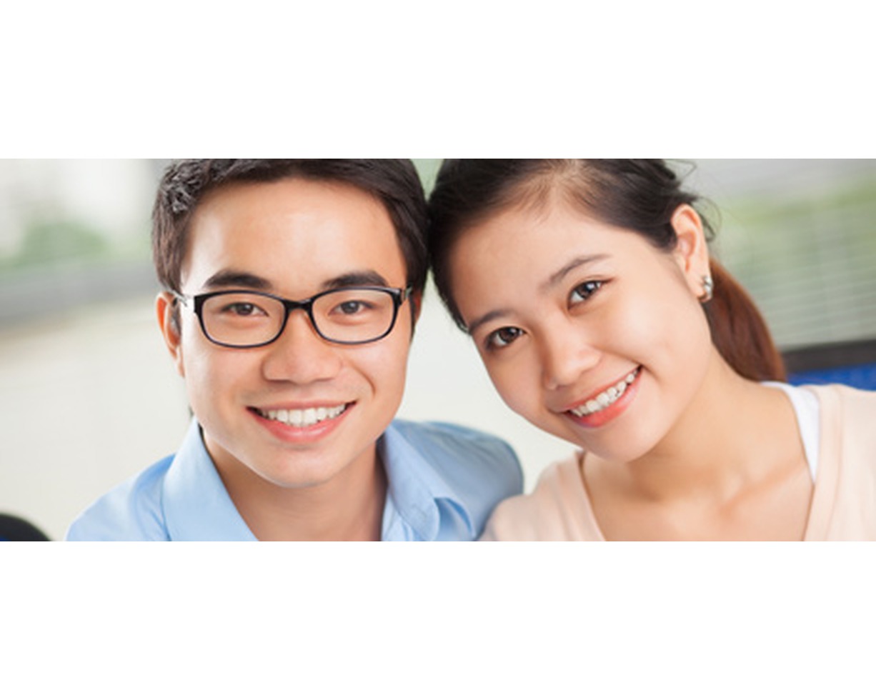 Young couple smiling closely together, both showing healthy teeth