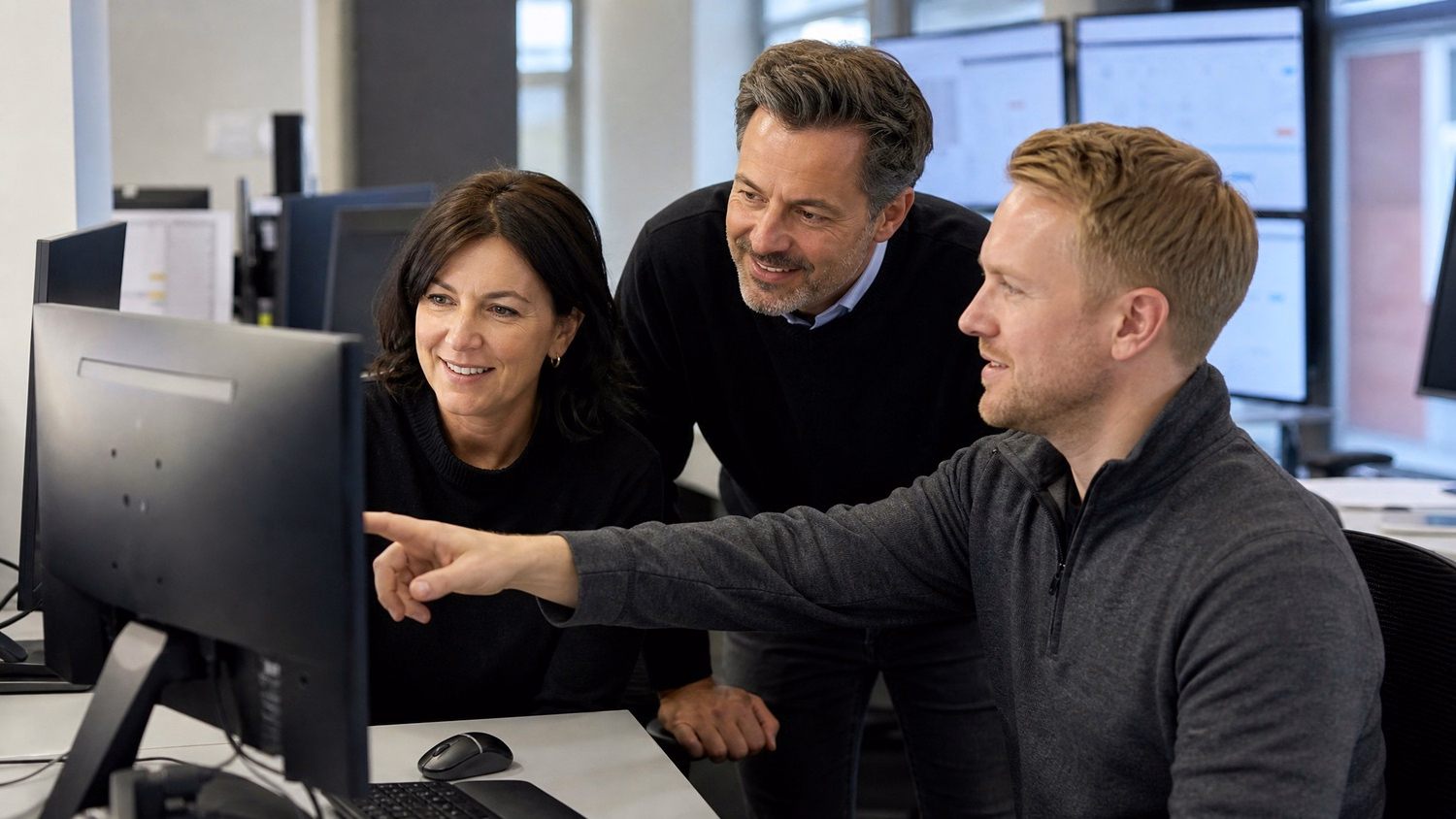 Two colleagues review suspicious email alerts on monitor