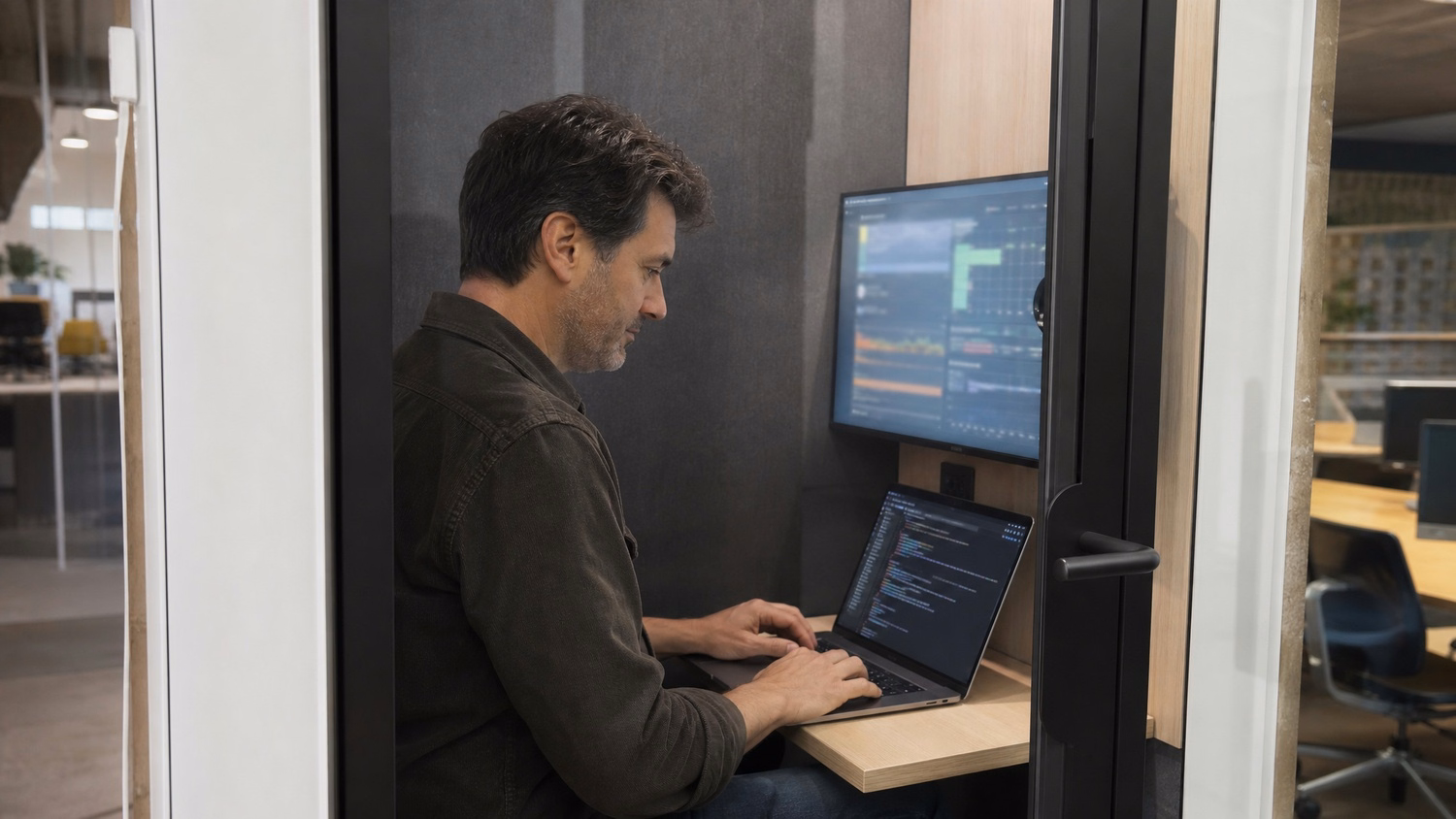 Man types script on laptop in quiet soundproof pod