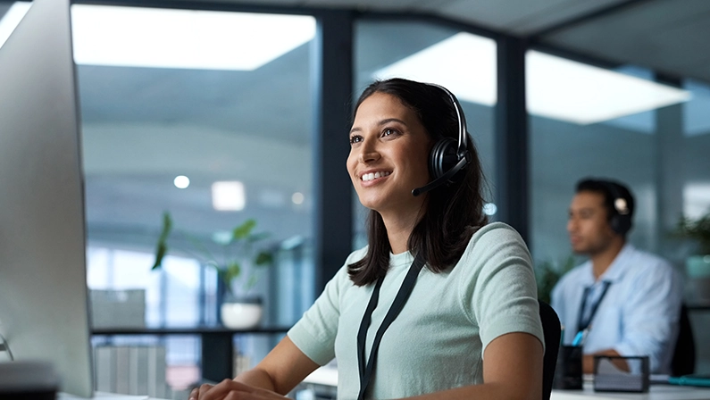 Another day, another happy client. Shot of a young woman using a headset and computer in a modern office.