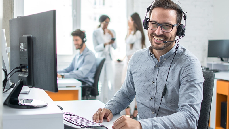 Happy young male customer support executive working in office.