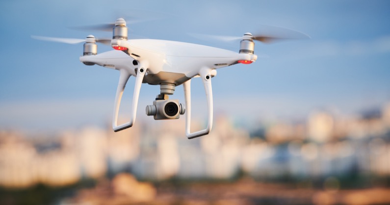 drone with digital camera flying at city street