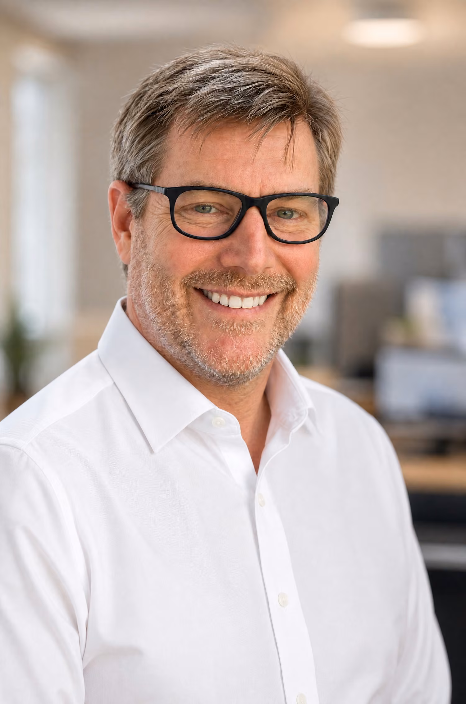Smiling IT professional in white shirt and glasses representing Protected Trust managed services team in Orlando