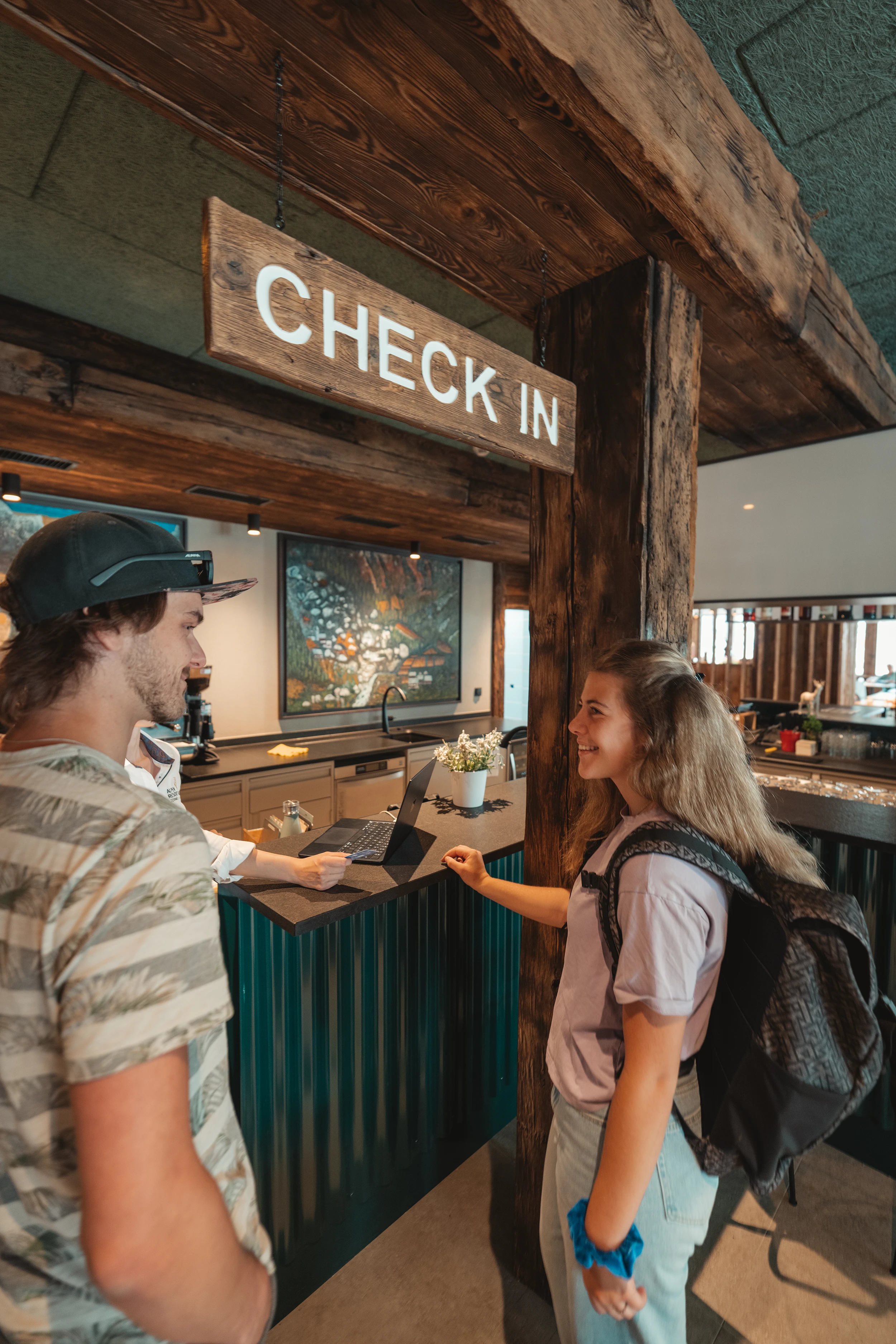 Gäste am Check-in-Schalter mit Holzschild an der Rezeption im Matterhorn Inn in Täsch