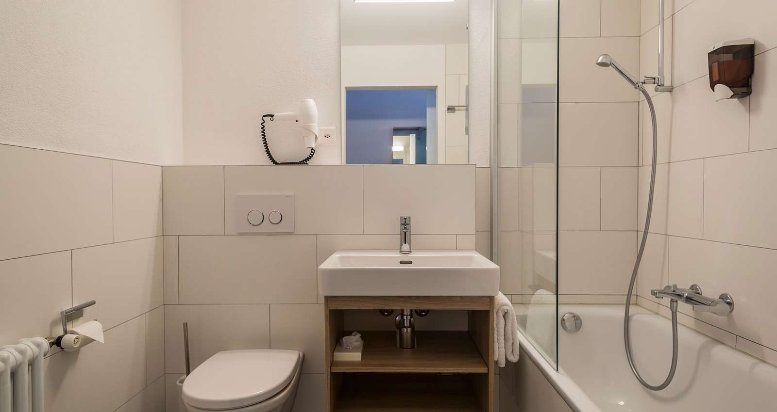 Badezimmer mit Badewanne, Duschwand, Lavabo und WC im Superior Doppelzimmer des Matterhorn Inn in Täsch