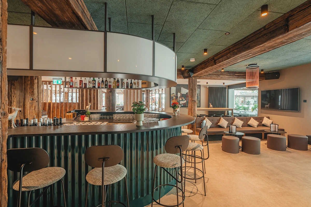 Modern gestaltete Hotelbar im Matterhorn Inn Täsch mit stilvoller Rund-Bar, gemütlicher Lounge-Ecke und alpinem Holz-Interieur – ideal für den Apéro nahe Zermatt.