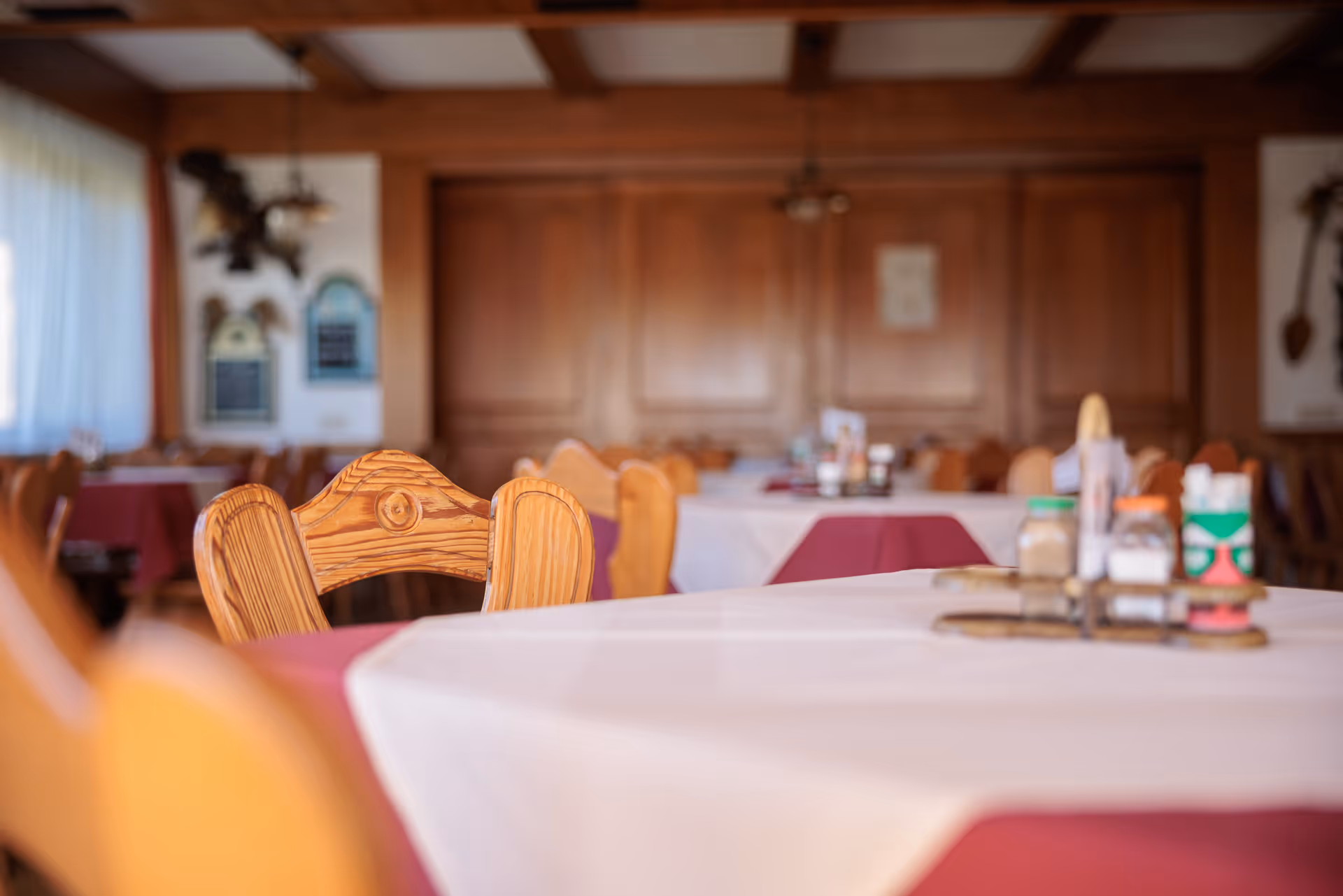 Holzvertäfelter Gastraum mit gedeckten Tischen im Restaurant des Alpengasthof Postl