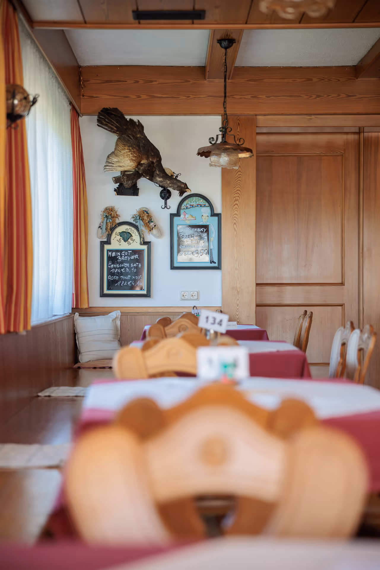 Gemütliche Gaststube mit gedeckten Tischen und Jagdtrophäen im Gasthof Postl auf der Hohen Wand