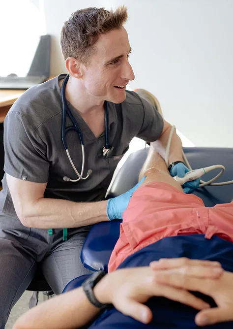 Medical professional with stethoscope performing an ultrasound scan on a patient's leg.