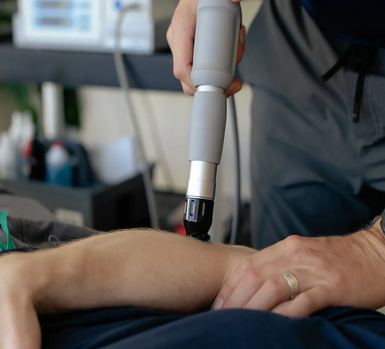 Person receiving therapy with a handheld device applied to their forearm.