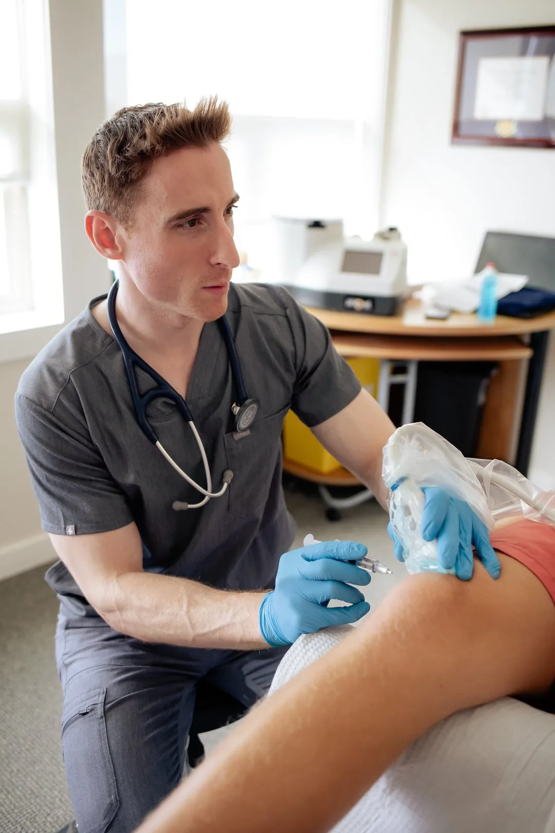 Medical professional wearing gloves giving an injection to a patient's upper arm in a clinic room.
