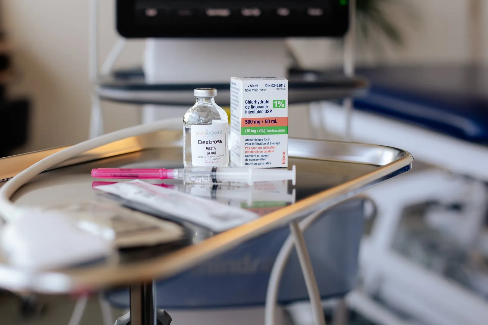 Medical tray with a vial of dextrose, lidocaine injection box, and a syringe with a pink needle cap.