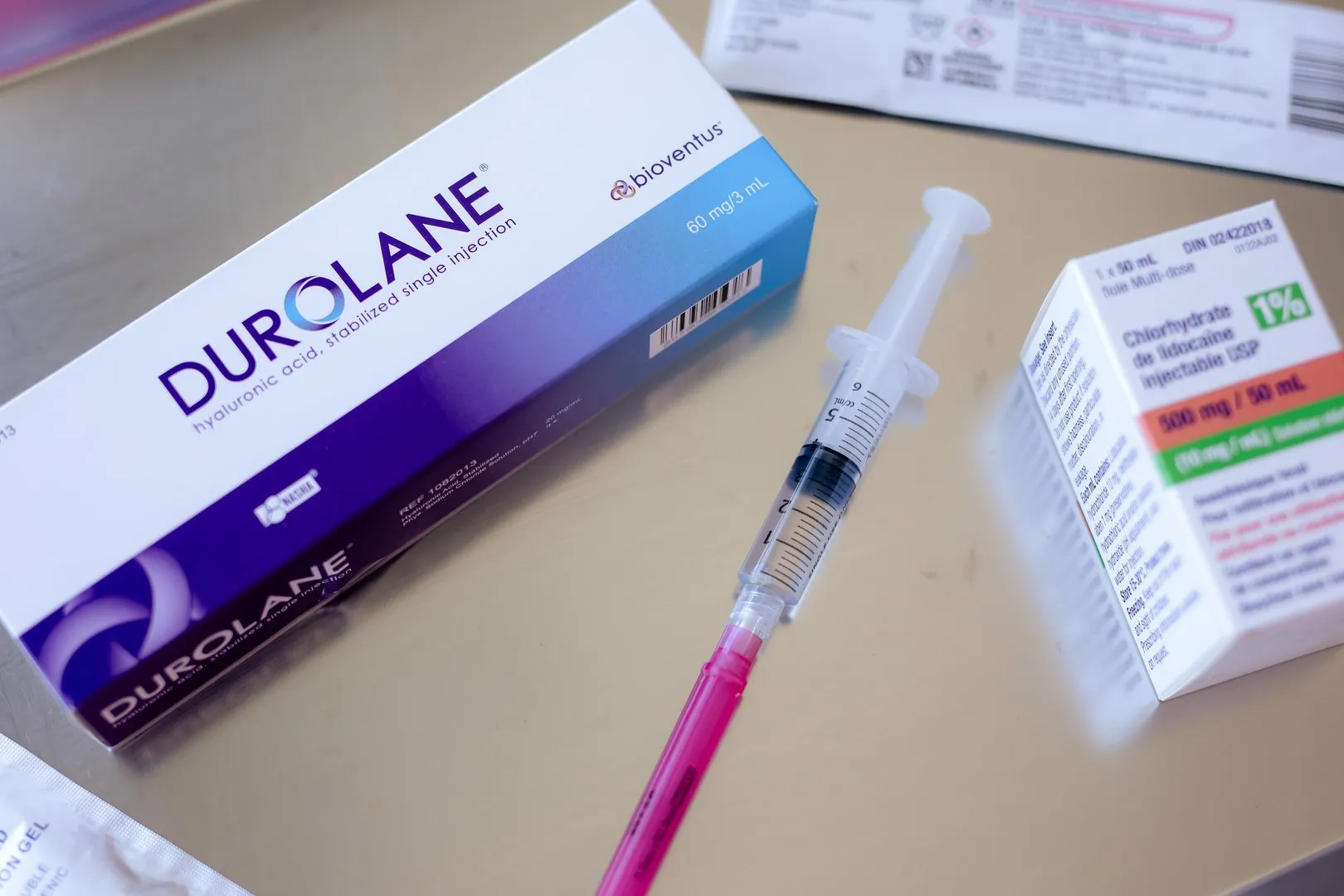 Box of DUROLANE hyaluronic acid injection, syringe with pink needle, and lidocaine injectable box.