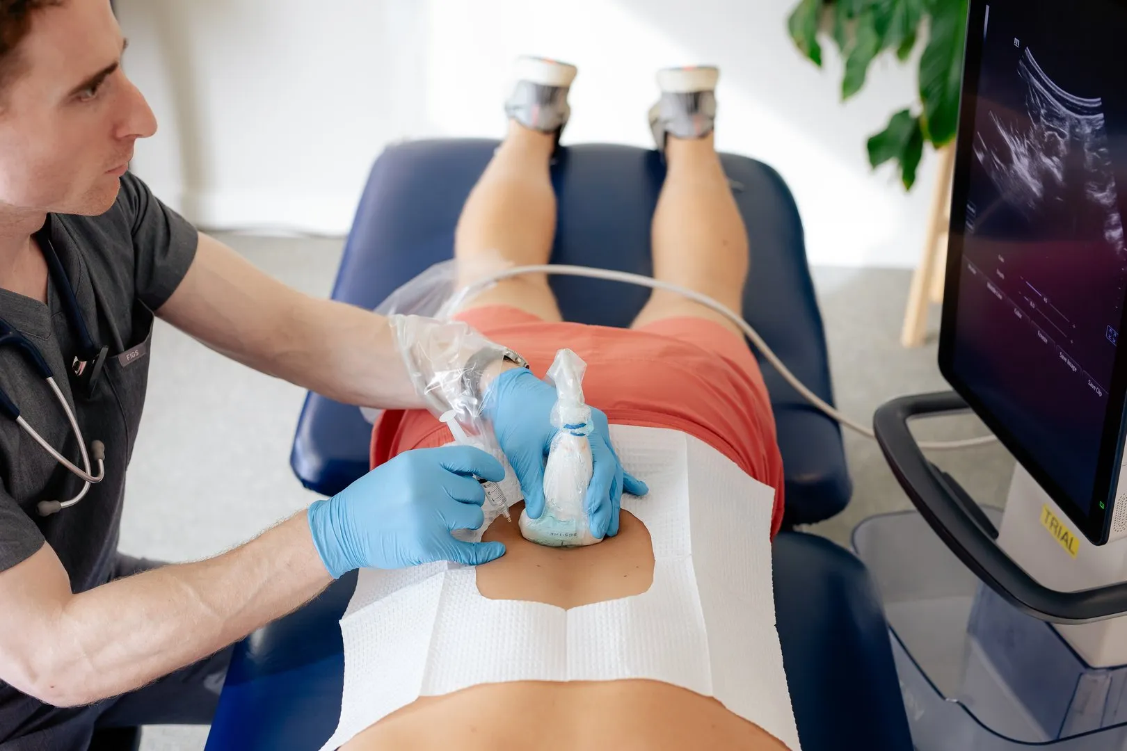 Medical professional performs an abdominal ultrasound on a patient lying on a medical table.