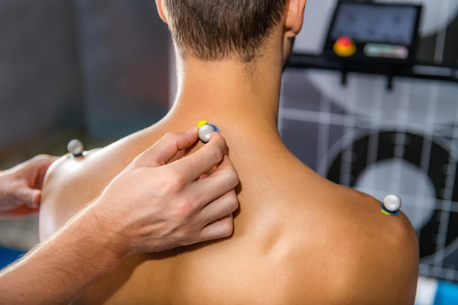 Hand attaches reflective marker to a person's upper back for motion capture analysis.