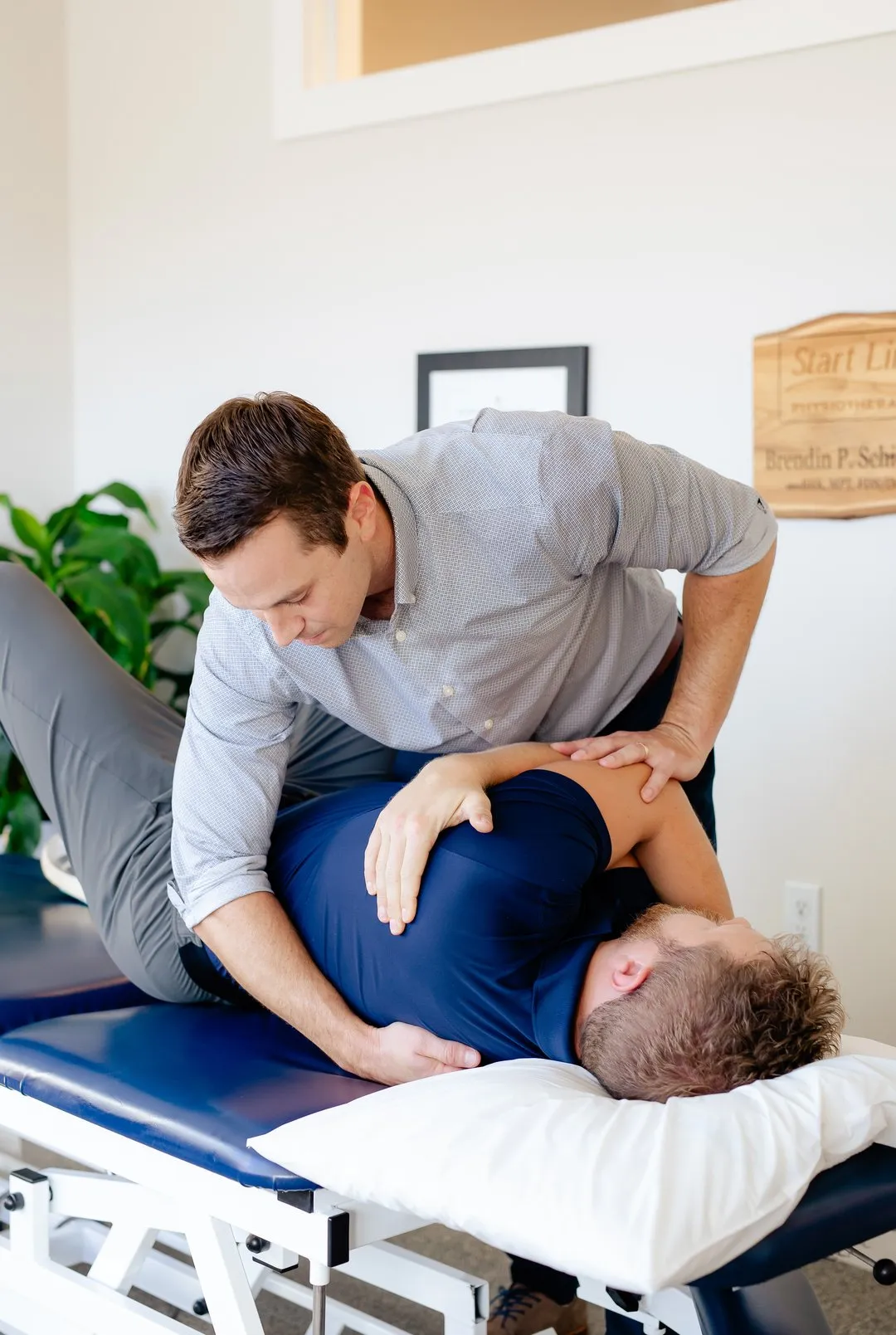 Chiropractor adjusting a man's back while he lies on a treatment table with a pillow.