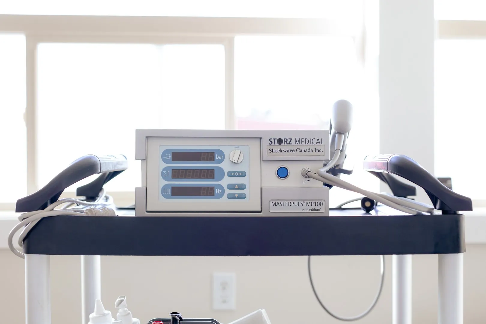 Medical device STORZ MEDICAL MASTERPULS MP100 elite edition on a black cart with cords attached.