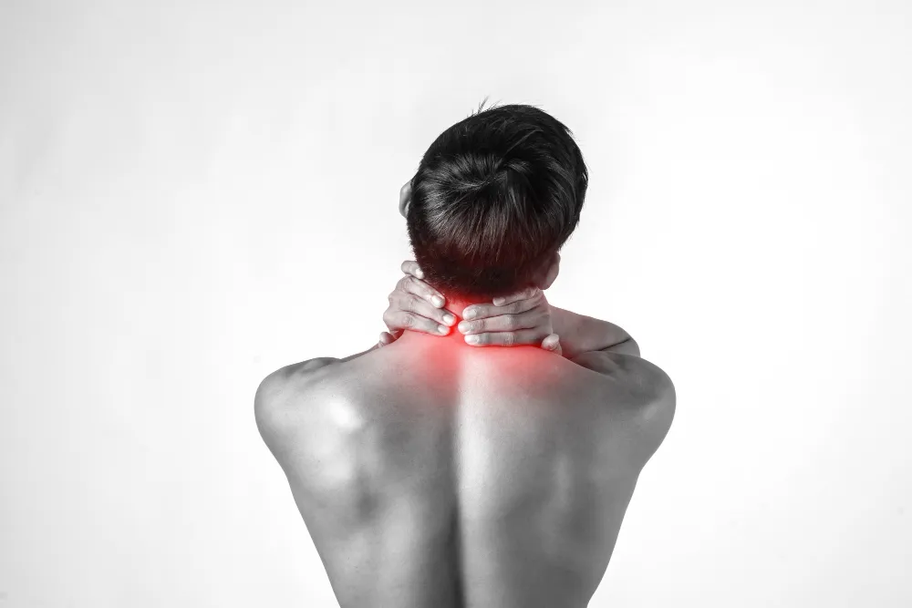 Man shown from behind holding his neck with red highlighting indicating neck pain or discomfort.