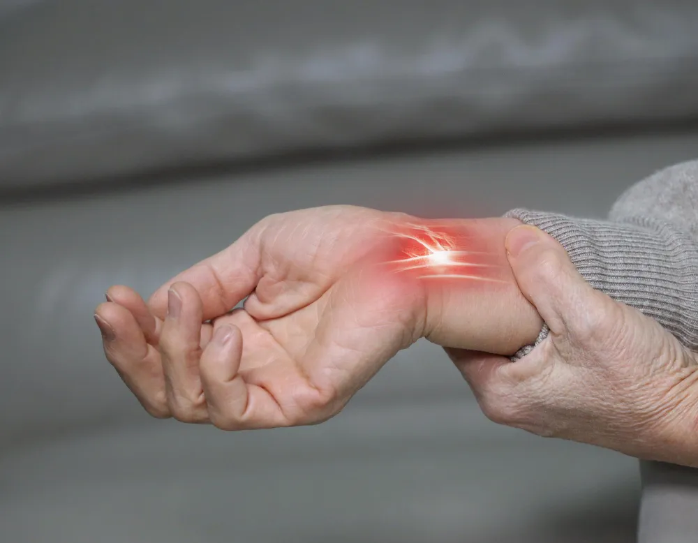 Older person holding wrist with glowing red pain indicating inflammation or injury.