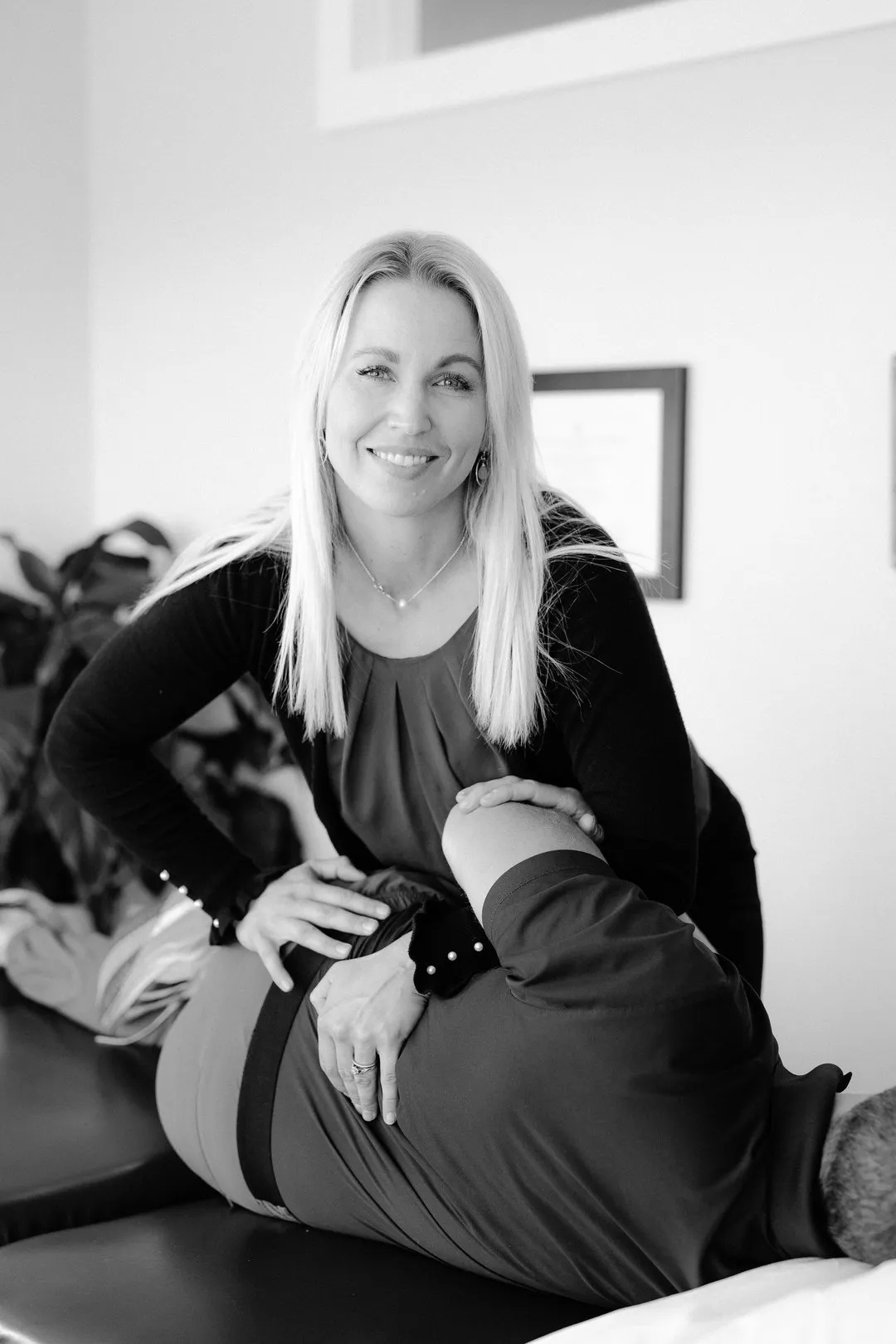 Smiling therapist adjusting a patient’s back on a treatment table in a clinical setting.