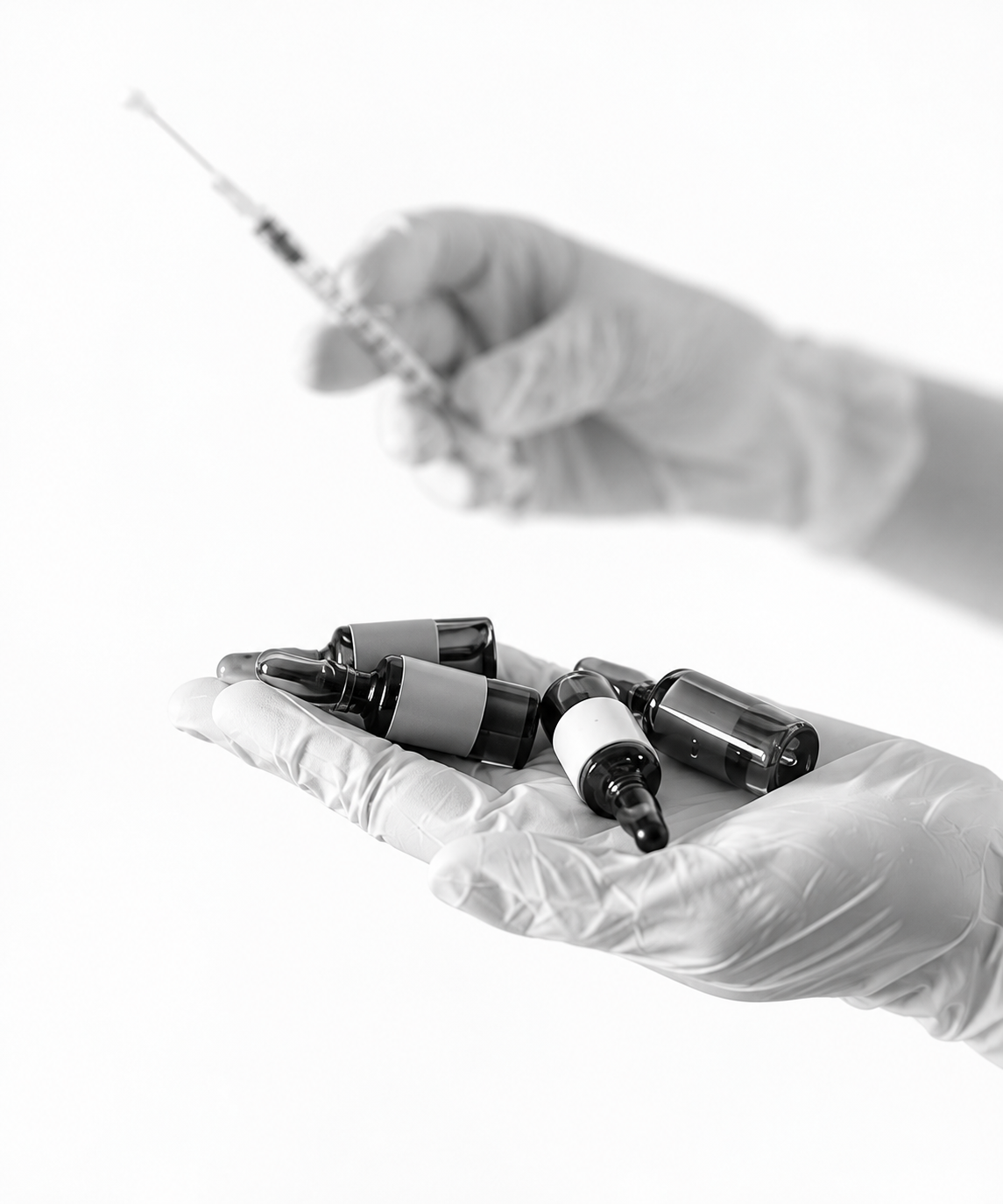 Healthcare professional holding several medication vials while preparing a syringe for injection therapy.