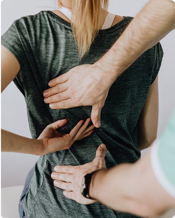 Physical therapist performing a hands-on assessment of a patient’s upper and lower back during a rehabilitation session.