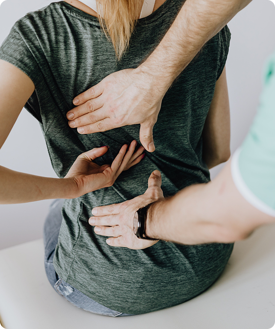 Physical therapist performing a hands-on assessment of a patient’s upper and lower back during a rehabilitation session.