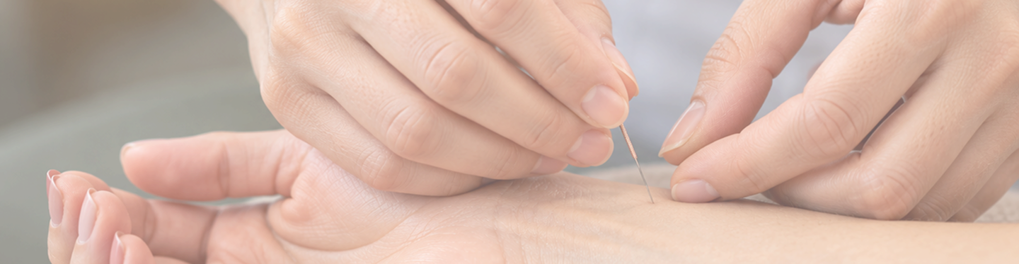 Close-up of an acupuncturist inserting a thin needle into a patient’s wrist during treatment.