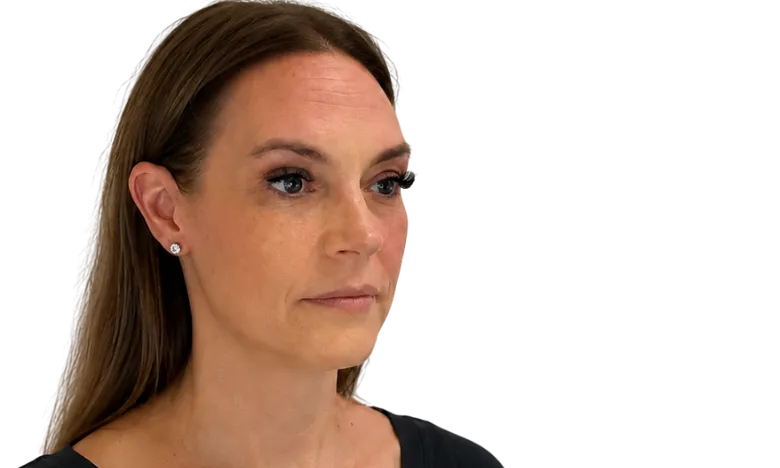 Woman with long brown hair wearing small round silver earrings and a serious expression.