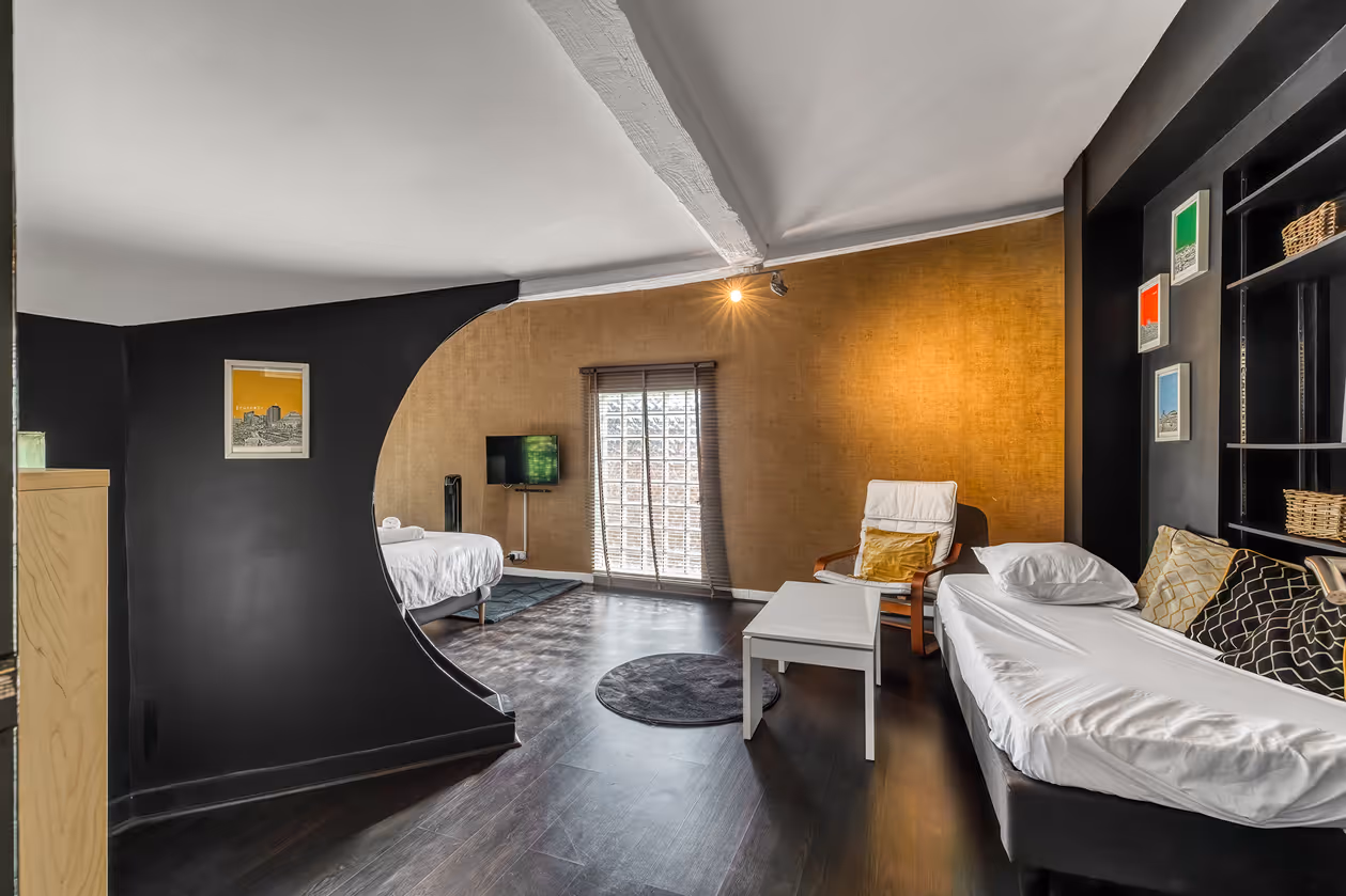 Salon moderne avec un mur doré, un canapé blanc, une chaise, une table basse et une télévision.