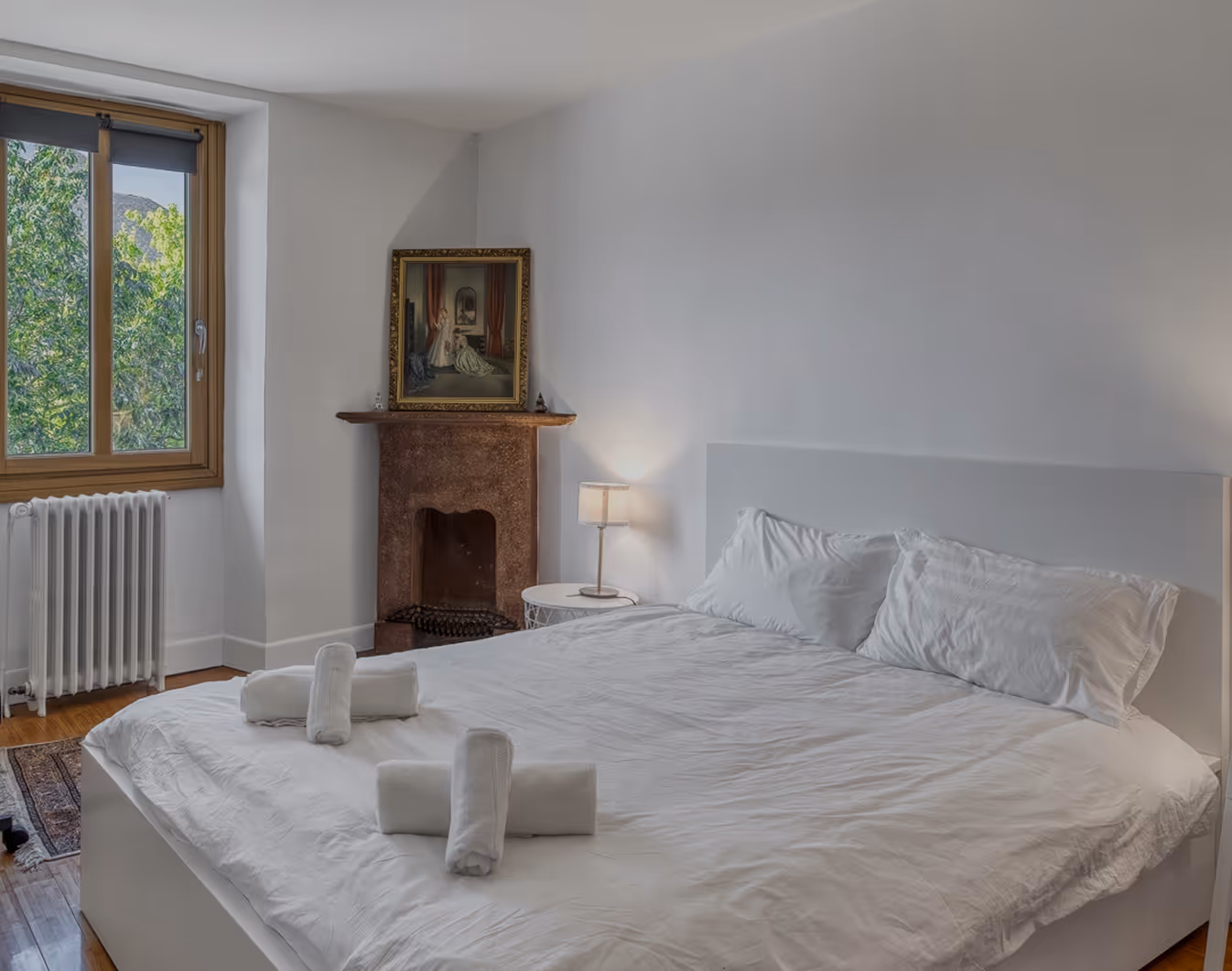 Chambre avec lit double bleu, grandes fenêtres, rideaux gris et affiche rouge «Keep Glam and Rock On».