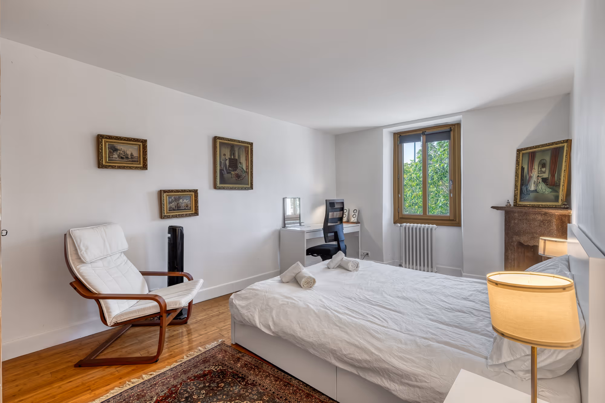 Chambre moderne avec grand lit blanc, murs gris foncé et lampes murales allumées.
