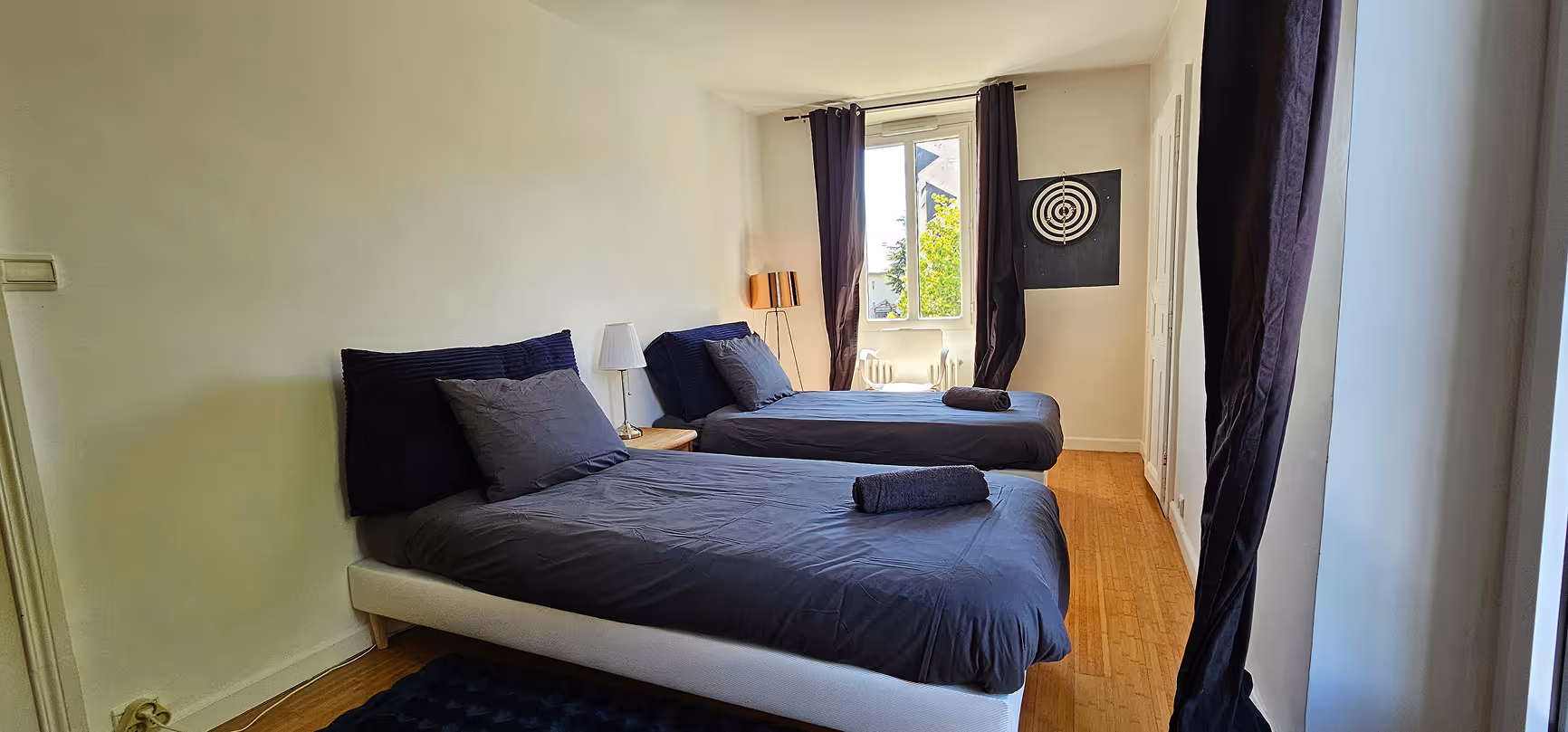 Salon moderne avec canapé, fauteuil, table basse, un lit en arrière-plan et une grande fenêtre.